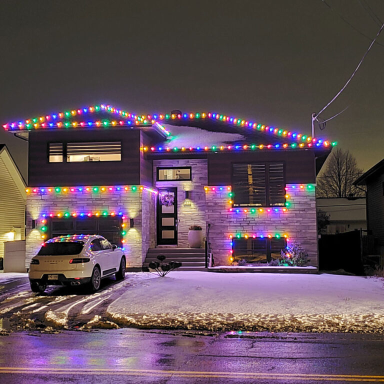 Christmas lights on home with white car in front of it